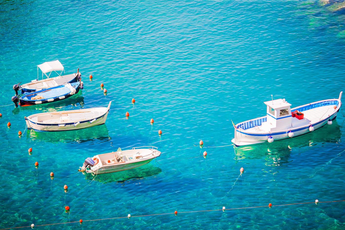 Beautiful cozy bay with boats and clear turquoise water in Italy